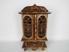 A small, Asian, table top cabinet, intricately carved and with mother of pearl inlay,