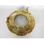 A heavy brass and glass porthole window,