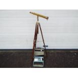 A brass telescope on wood and brass tripod and a vintage portable typewriter.