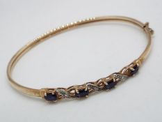 A 9 carat gold bangle with hinge fastening set with sapphires and diamonds,