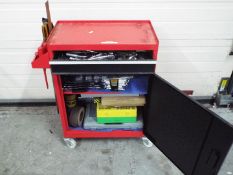 A red metal too cabinet / chest on castors, approximately 73 cm x 61 cm x 29 cm, with contents.