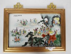 A framed ceramic tile / plaque decorated with numerous figures and auspicious symbols, signed,