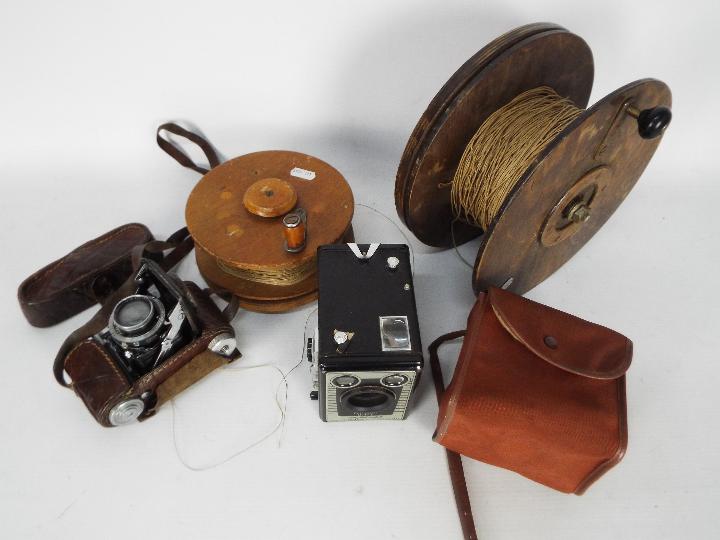 Two vintage wooden kite reels, largest approximately 23.5 cm (d) and two cameras.