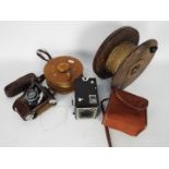 Two vintage wooden kite reels, largest approximately 23.5 cm (d) and two cameras.