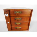 A small four drawer chest / collectors cabinet measuring approximately 31 cm x 30 cm x 26 cm.
