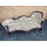 A floral upholstered, mahogany chaise longue with carved decoration,
