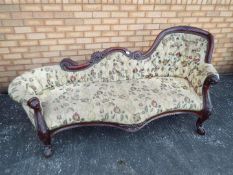 A floral upholstered, mahogany chaise longue with carved decoration,