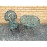 A cast metal garden table and chair.