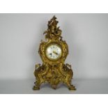 A French Rococo styled brass cased mantel clock, the case decorated with scrolls,
