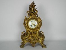 A French Rococo styled brass cased mantel clock, the case decorated with scrolls,