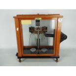 An L Oertling precision balance, model 62FM, in glazed mahogany case,