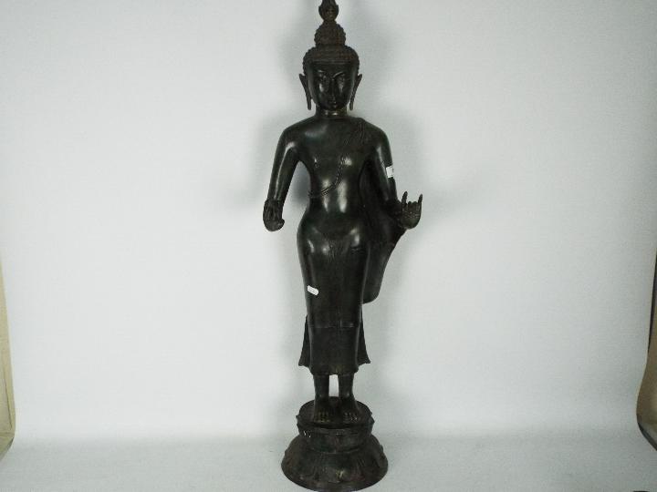 A large metal standing Buddha atop double lotus base,