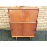 A mid century writing bureau with fall front over enclosed cupboard section,