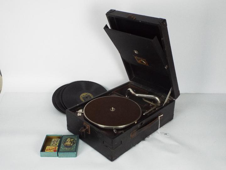 A HMV portable, table top gramophone with a small quantity of records and additional needles.