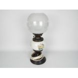 A converted oil lamp with ceramic reservoir with floral decoration and glass shade,