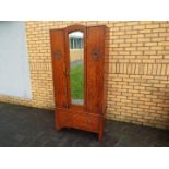 A wardrobe with mirrored door, carved decoration and lower drawer,