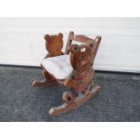 A child's carved wood rocking chair, the sides in the form of bears.