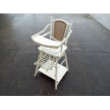 A white painted metamorphic high chair with cane back.