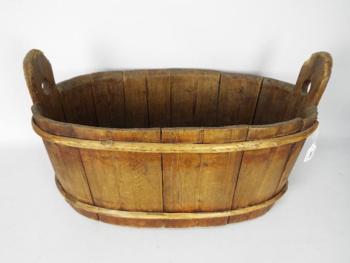 A vintage, oval wooden trough, approximately 33 cm x 60 cm x 37 cm.