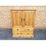 A twin door pine cupboard, with two lower drawers, approximately 114 cm x 91 cm x 46 cm.