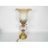 A brass and glass oil lamp (converted) with peach tinted glass shade,