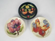 Moorcroft - Three Moorcroft Pottery coasters comprising a Magnolia pattern,