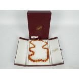 A graduated amber bead necklace, contained in presentation box, approximately 66 cm (l),