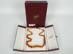 A graduated amber bead necklace, contained in presentation box, approximately 66 cm (l),