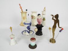 A collection of hat pin stands, predominantly ceramic,