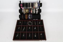 Costume Jewellery - a jewellery display containing predominantly silver charms and a bracelet