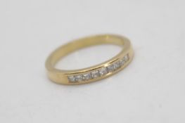 A yellow metal (presumed 14ct) diamond set half eternity ring with nine princess cut stones