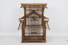 A decorative wooden bird cage containing taxidermy bird,