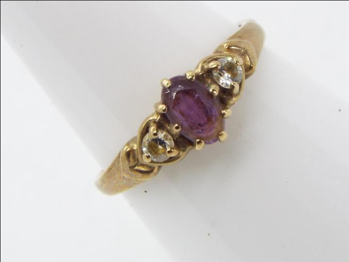 A hallmarked 9 carat yellow gold trilogy ring set with amethyst flanked by two cz stones, size M,