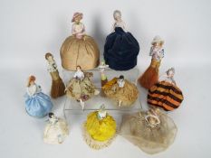 A collection of early 20th century porcelain half doll pin cushions and half doll crumb brushes.