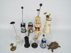 A collection of various hat pin stands to include ceramic, glass, ebony,