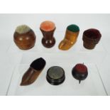 A collection of treen pin cushions to include two ebony examples,