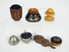 Five small pin cushions to include one carved nut example, a circular section,