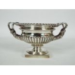 A George VI silver pedestal urn with twin sinuous handles and gadrooned decoration,