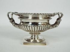 A George VI silver pedestal urn with twin sinuous handles and gadrooned decoration,