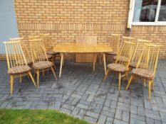 Ercol - An extending dining table with ten Goldsmith chairs,