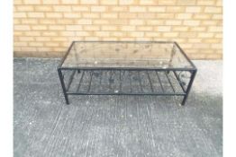 A glass topped, black framed coffee table, approximately 40 cm x 110 cm x 55 cm.