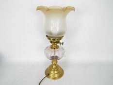 A brass and glass oil lamp (converted) with peach tinted glass shade,