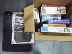 A collection of boxed jigsaw puzzles and three portable jigsaw puzzle boards.
