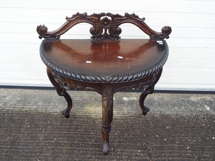 A demi lune console table with carved decoration on tripod supports,