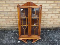 A glazed wall hanging corner cabinet, approximately 105 cm x 58 cm x 32 cm.