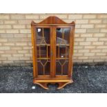 A glazed wall hanging corner cabinet, approximately 105 cm x 58 cm x 32 cm.