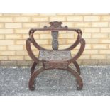 A highly carved X frame or Savonarola type chair with carved decoration of fruiting vine and turned