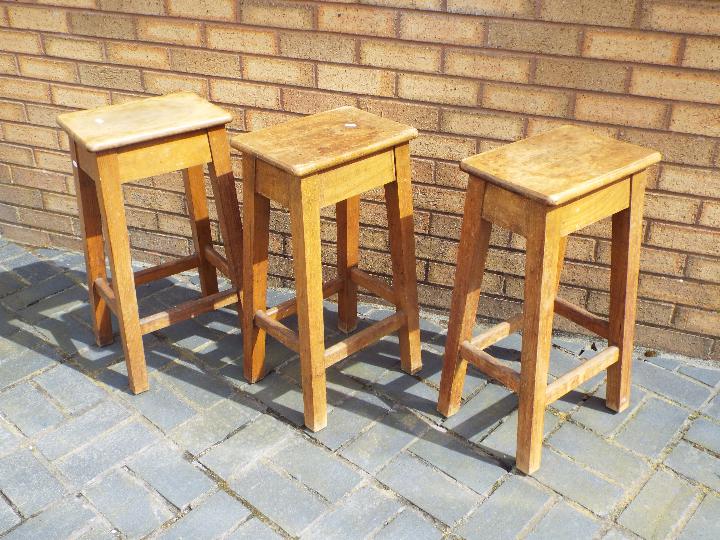 Three 20th century laboratory style wooden stools.