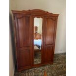 A triple wardrobe with external mirror to central door,