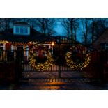 A green lightly frosted wreath illuminated with warm white lights and plug.